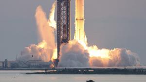 SpaceX Starship on the launch pad during engine light-off, with the tower visible